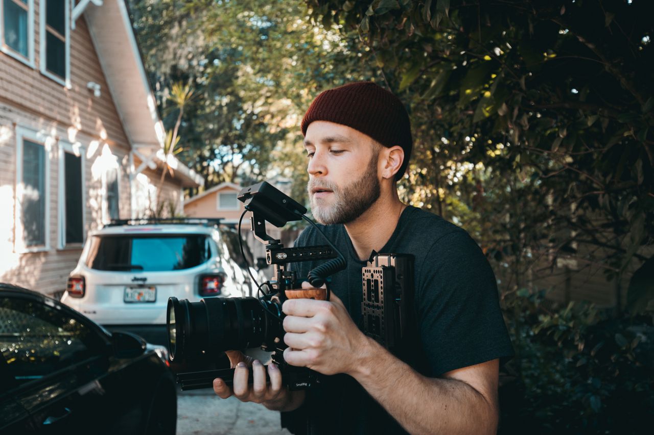 Videographer with camera gear filming outdoors, capturing a creative scene.