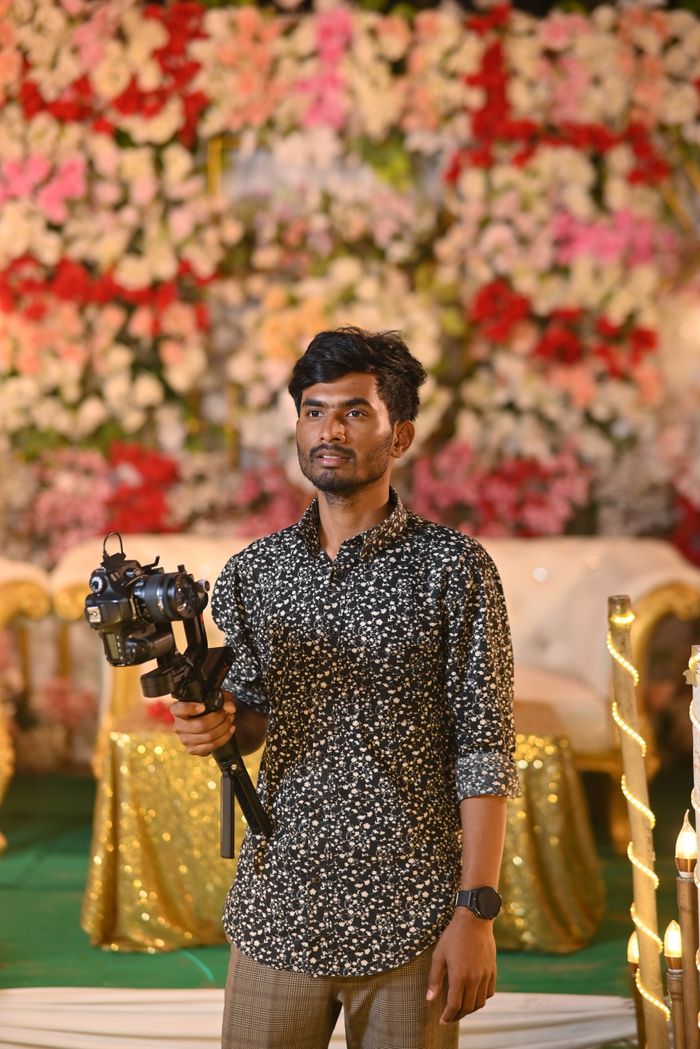 Male photographer with camera at an indoor floral event. Vibrant and colorful setting.