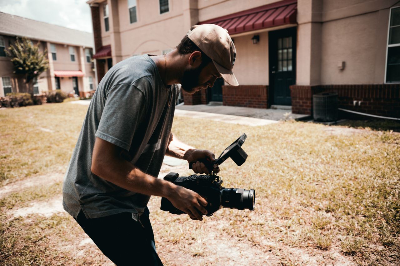 A filmmaker using professional camera gear during an outdoor video shoot.